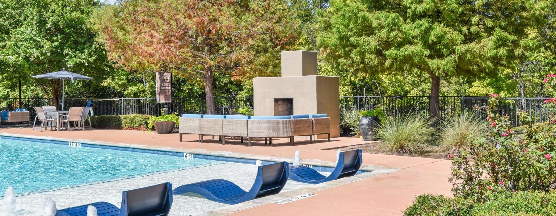 a swimming pool with a bench and trees around it