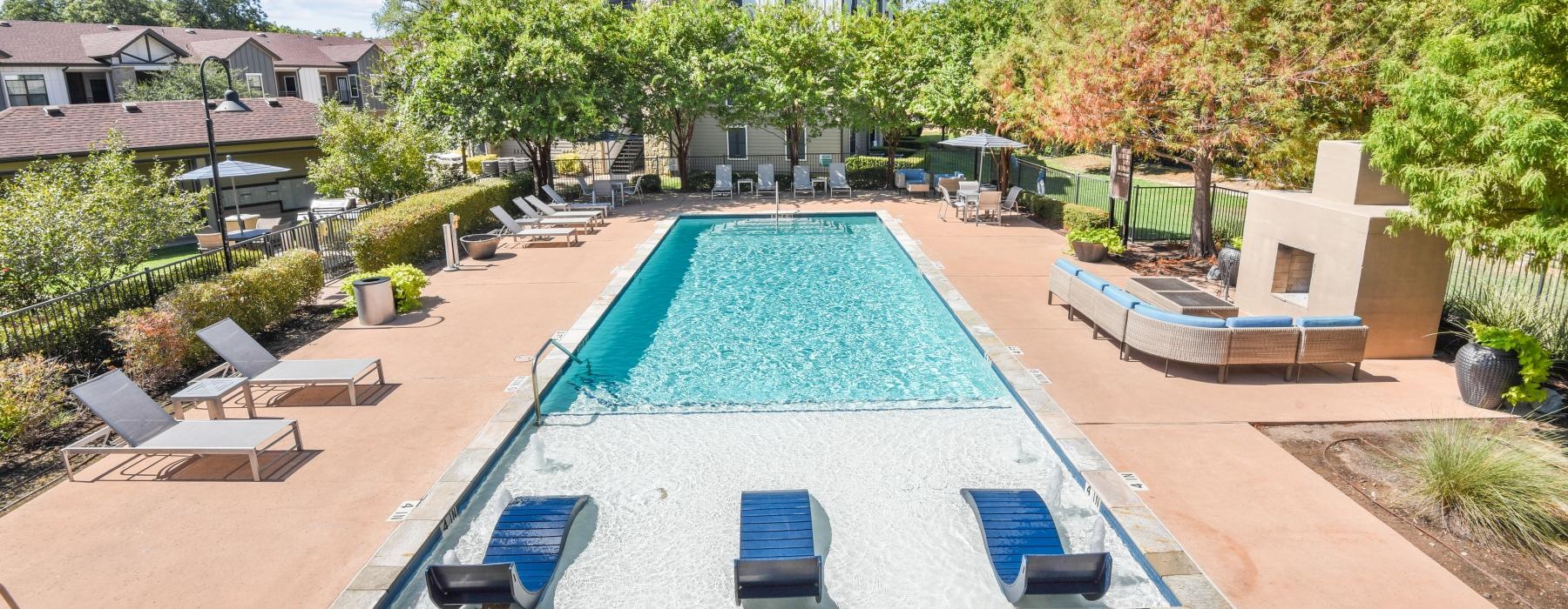 a swimming pool with chairs and a building in the background